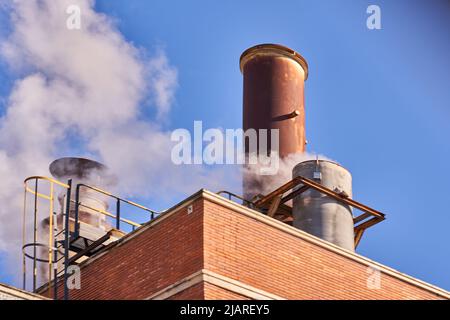 Industrial chimney releasing fumes, steam and polluting gases Stock Photo