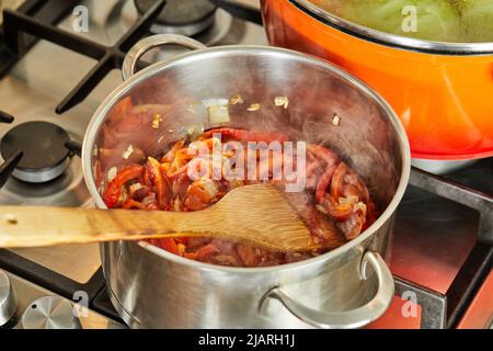 Onions and bell peppers are fried in saucepan according to recipe from the Internet for cooking Stock Photo