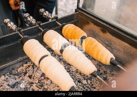 Trdelnik or trdlo Czech pastry buns with fragrant sprinkling of cinnamon, nuts and sugar, cooked on grill. soft focus. Sweet pastry roasting Stock Photo