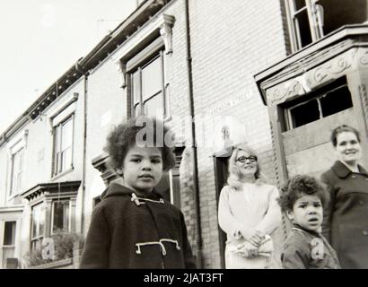 Two women and two young boys watch an anti racism demonstration march through Leicester,  England, United Kingdom, British Isles, in 1972. Stock Photo