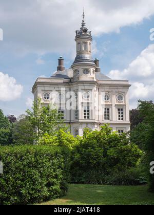 Beveren, Belgium, May 22, 2022, Hof Ter Saksen castle, with blue sky and a field of clouds and in the foreground the garden with tall plants Stock Photo