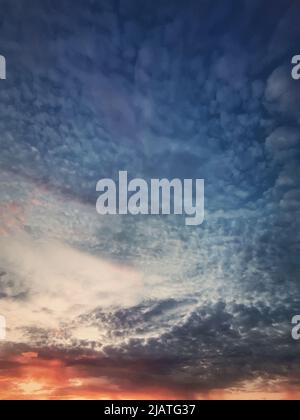 Dreamlike sunset sky vertical background with fluffy and colorful cirrus clouds above the horizon. Sunrise celestial view Stock Photo