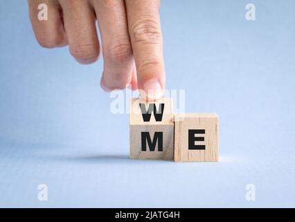 Fingers flip wooden cube with word me to we. Teamwork concept. Stock Photo