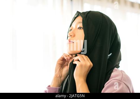 Beautiful muslim woman wearing and putting on her head scarf. Stock Photo