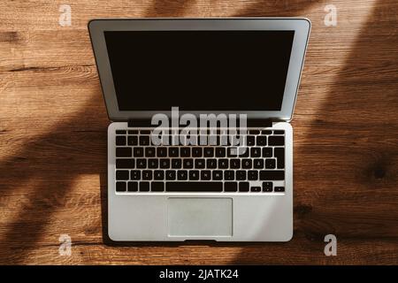 Top view of laptop computer on office desk with blank black mockup screen and copy space, flat lay Stock Photo