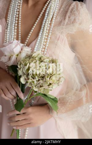 A woman wearing a pink vintage gown and holding flowers Stock Photo