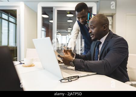 Two African American business partners are working on a laptop together on a common project. Coworking, social contacts and remote networking Stock Photo