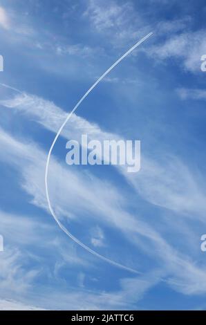 curving vapour trail on blue sky and white clouds Stock Photo