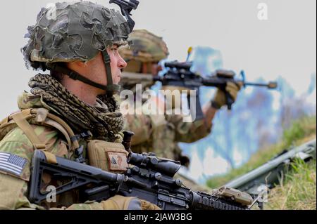 Bemowo Piskie Training Area, Orzysz, Poland - Marine Corps Cpl. Corey, Verplanck (left), and Cpl. Ura Virgilio (right), a Marine and Soldier a part of Headquarters, Headquarters Company, 185th Infantry Division, California Army National Guard, Battlegroup Poland, surveys the area during the last training day of exercise Thunderbolt Focus 2022, April 27. U.S. Soldiers among others from allied nations worked together in dynamic teams against tactics, techniques, and procedures used by enemy forces that allowed the Battle Groups to practice, refine, and validate all warfighting, interoperability Stock Photo