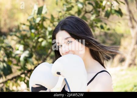 young female boxer with white gloves in a park Stock Photo