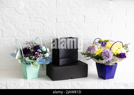 black empty paper bags and bouquets. Blank wall Stock Photo