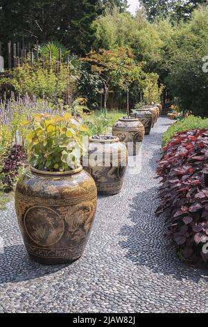 Leiden, Netherlands - July 25, 2021: Large Chinese-style floor vases on a garden path. Stock Photo