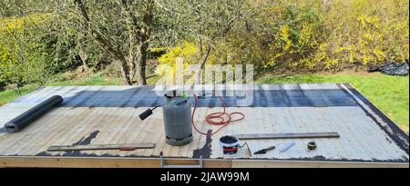 Roofing felt welding on bitumen roof roof repair with roofing felt and open flame propane tool on flat roof, leak with free space for text Stock Photo