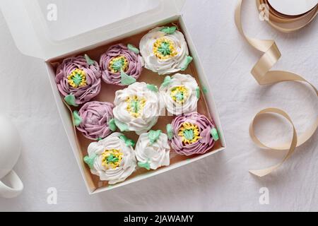 An opened gift box of zephyr flowers - marshmallow peonies on a white table Stock Photo