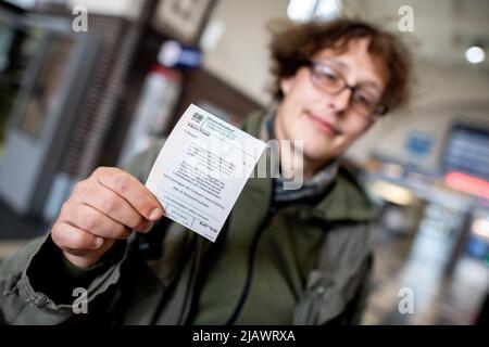 Oldenburg, Germany. 01st June, 2022. Passenger Jannis holds a 9-euro Deutsche Bahn ticket in his hand at the main train station. Travelers can use the 9-euro ticket for journeys on local transport. In June, July and August, journeys with these tickets are possible throughout Germany. Credit: Hauke-Christian Dittrich/dpa/Alamy Live News