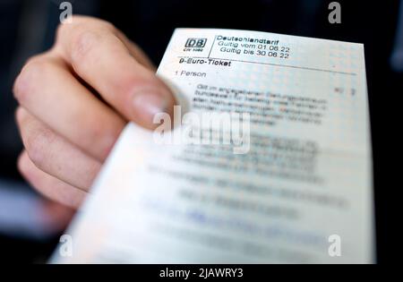 Oldenburg, Germany. 01st June, 2022. A young man holds a 9-euro Deutsche Bahn ticket in his hand at the main train station. Travelers can use the 9-Euro-Ticket for journeys on local transport. In June, July and August, journeys with these tickets are possible throughout Germany. Credit: Hauke-Christian Dittrich/dpa/Alamy Live News