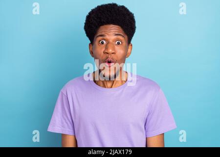 Photo of impressed pretty dark skin guy dressed purple t-shirt big eyes isolated blue color background Stock Photo