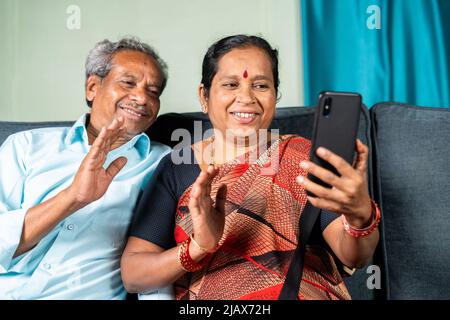 Senior couple busy making video call on mobile phone from home - concept of communication, technology and active lifestyle. Stock Photo