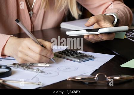 The girl holds the phone in her hands and makes a bar chart and reports on the robot at the table, business and finance, technology and online sales Stock Photo