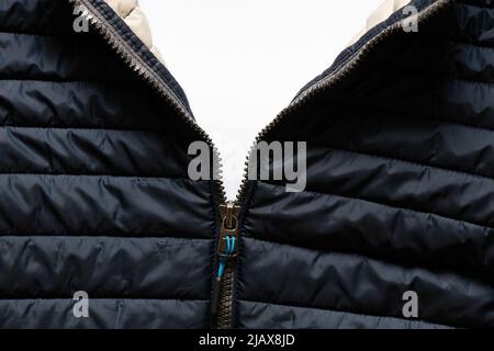 blue warm winter jacket with a lock in the middle as a background, clothes, a lock on Black jacket with unzipped zipper as background Stock Photo