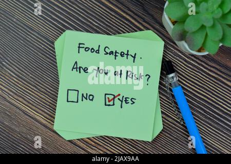 Concept of Food Safety. Are you at risk? Yes write on sticky notes isolated on Wooden Table. Stock Photo