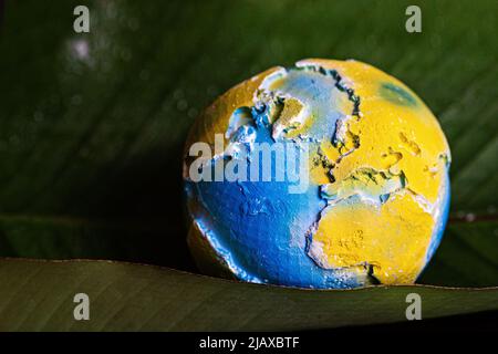 Earth planet lying on green leaves. Ecology, environment and Earth day concept.  Stock Photo