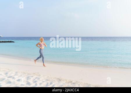 Athletic woman jogging on the beach. Stock Photo