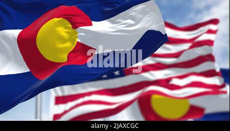 Colorado state flags waving along with the national flag of the United States of America. In the background there is a clear sky. Stock Photo