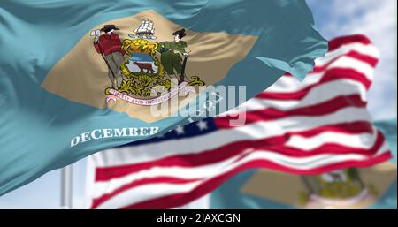 Delaware state flags waving along with the national flag of the United States of America. In the background there is a clear sky. Stock Photo