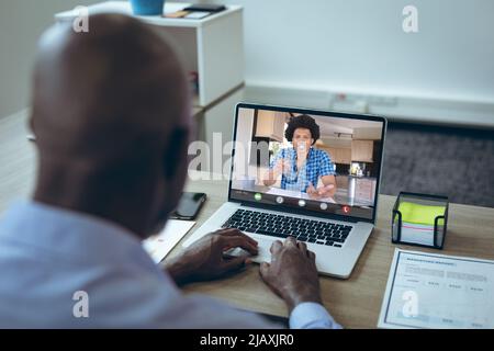 African american young male colleagues talking during video conference on laptop at desk in office Stock Photo