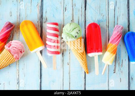 Selection of colorful summer popsicles and ice cream treats. Overhead view scattered on a rustic blue background. Stock Photo