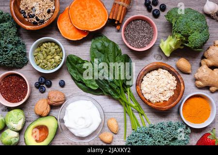 Group of healthy food ingredients. Overhead view table scene on a wooden background. Super food concept with green vegetables, berries, whole grains, Stock Photo