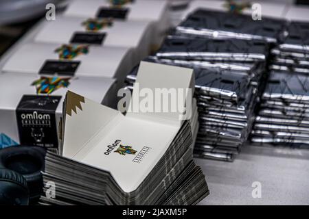 Foil-wrapped chocolate bars and unfolded cardboard boxes bearing the brand's colourful logo motif are stacked on a work table at the Omnom chocolate factory in Reykjavik, Iceland. Stock Photo