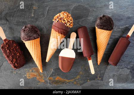 Variety of chocolate ice cream desserts. Overhead view scattered on a dark slate background. Stock Photo