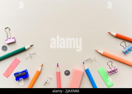 Top view blank office desk table with empty space on pastel beige backgroud. Flat lay. Paper clips, sharpener, pencils, stickers and other school supp Stock Photo