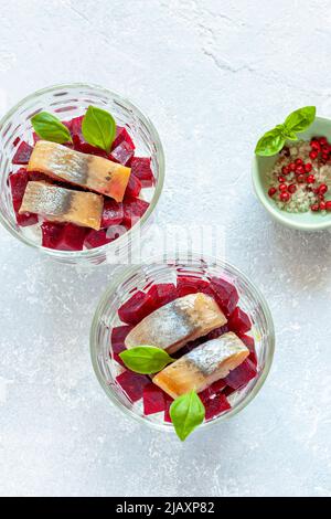 smoked hering and red beet salad served in glass bowls, top view, silver grey background, holiday dish idea Stock Photo