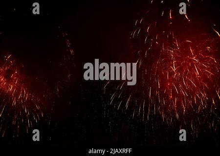 Colored night explosions in black sky. Fireworks in honor of Christmas or November 5th, July 4th on a black background. Stock Photo