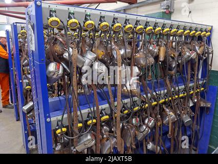 Multiple coal miners lamps on belts charging batteries, lamp room in a South Wales pit colliery Stock Photo