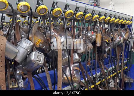 Multiple coal miners lamps on belts charging batteries, lamp room in a South Wales pit colliery Stock Photo