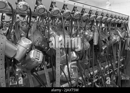 Multiple coal miners lamps on belts charging batteries, lamp room in a South Wales pit colliery Stock Photo