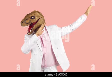 Weird guy wearing suit and funny dinosaur mask dancing and having fun at crazy party Stock Photo