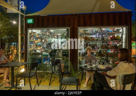 People sit in outdoor chairs enjoying Tucson's nightlife. Intentional camera blur from long exposure Stock Photo