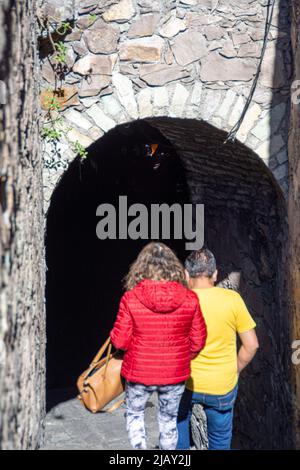 A couple enters one of the city's many underground tunnels that can be found underground throughout the municipality, Guanajuato, Guanajuato, Mexico. Stock Photo