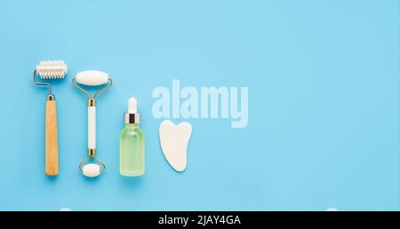 Set of massage roller and gua sha for face on blue background. Self care, skin care concept. Copy space for text, top view Stock Photo