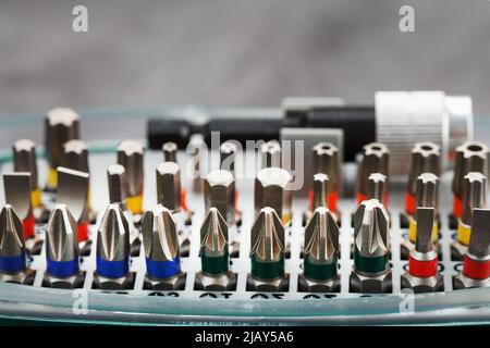 A set of metal power bits in a box on a gray background, for repair and maintenance Stock Photo