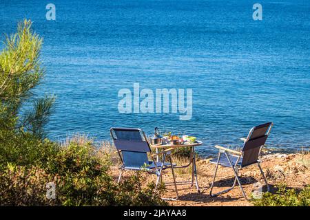 Breakfast table set up on the beach. Camping is done here. One summer morning. Location Cunda Island. Stock Photo