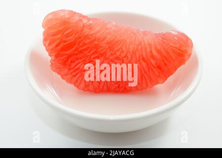 juicy red grapefruit slice on white saucer Stock Photo