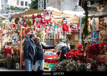 Barcelona, Spain – December 20, 2021: Christmas market on the square in front of Cathedral in Barcelona, couple in the mask selecting Christmas tree, Stock Photo