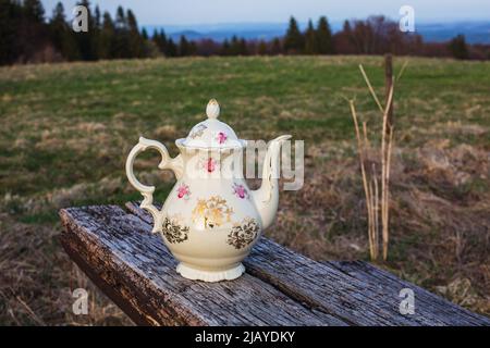 old antique teapot outside on rustic wooden table in nature Stock Photo