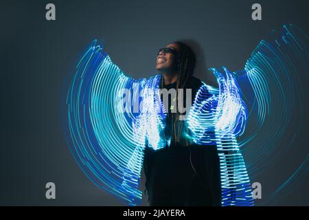 Smiling african american woman in smart glasses with abstract projection on grey background Stock Photo